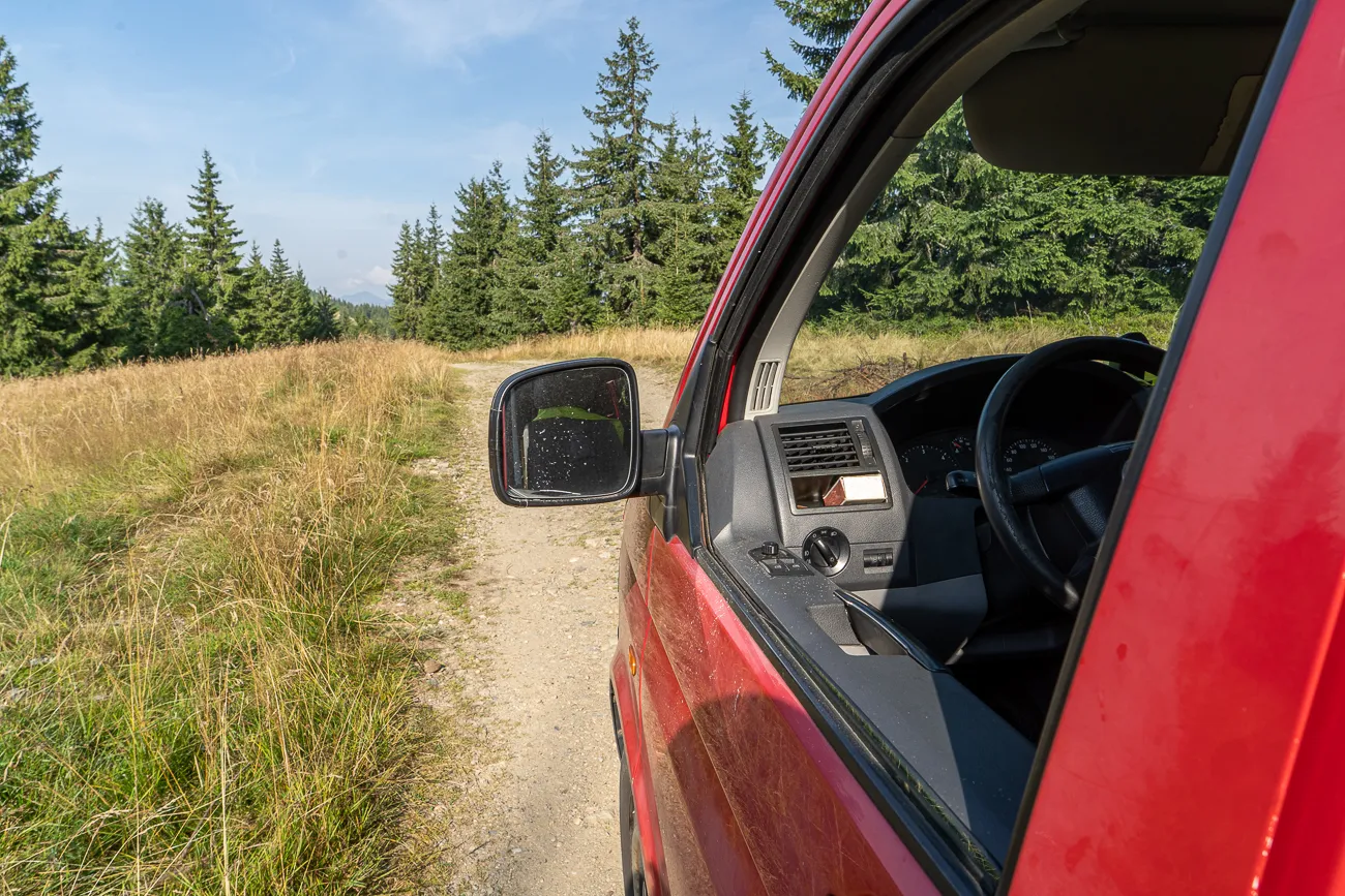 roter wagen auf unbefestigter strecke im bergland
