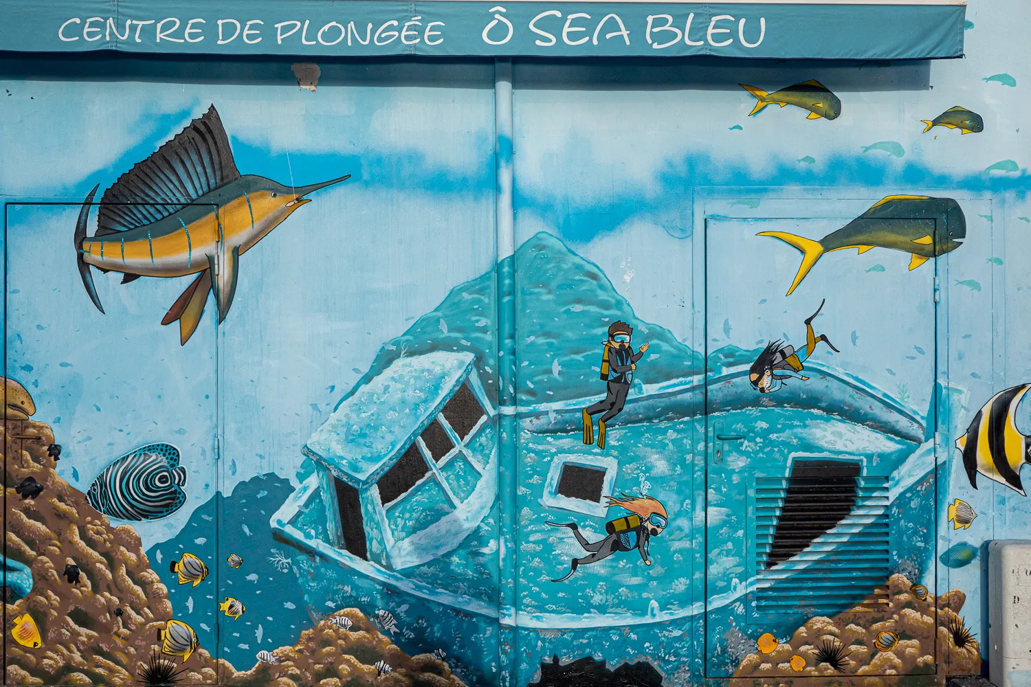 Mural mit Tauchern und Fischen vor Schiffswrack im blauen Wasser