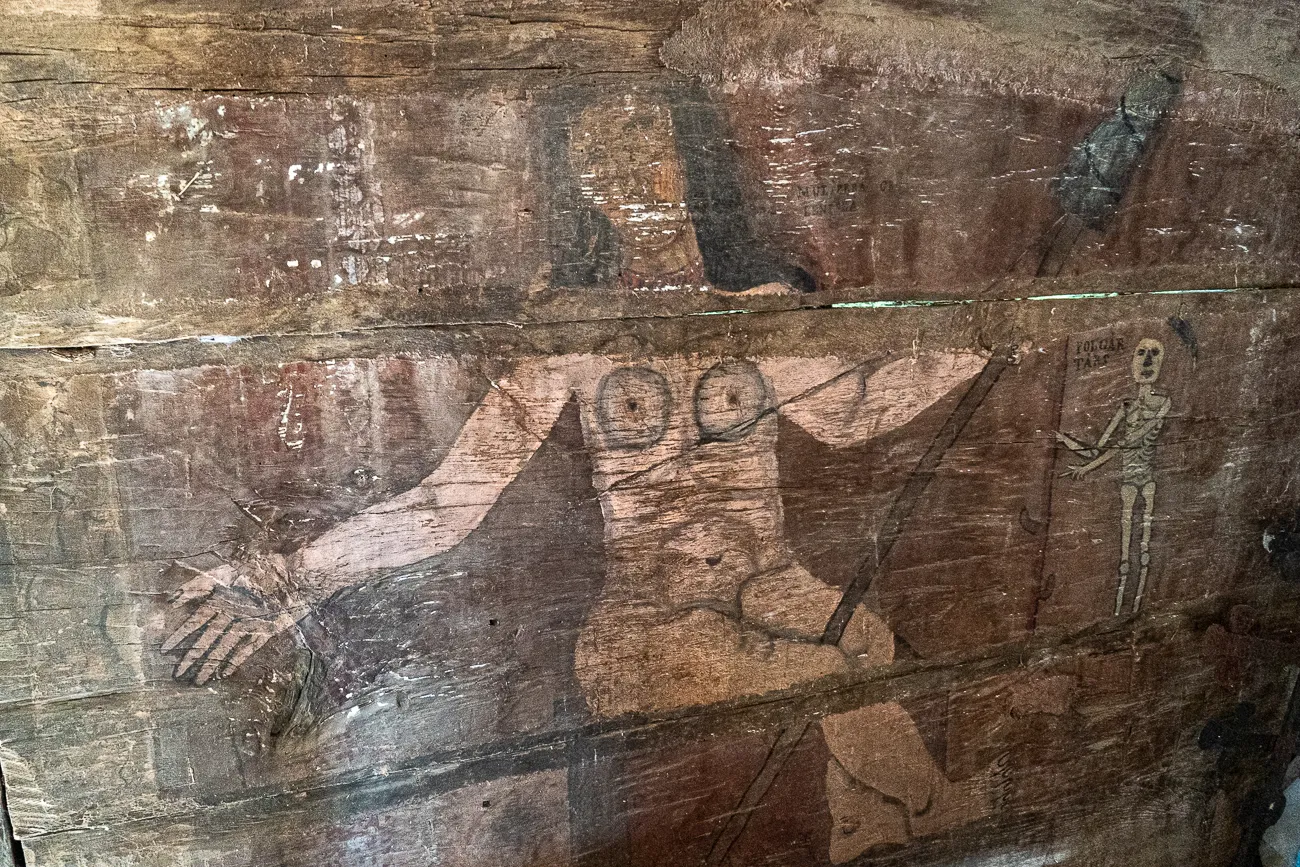 Alter Wandgemälde in einer Kirche mit stilisierten Figuren und Skelett.