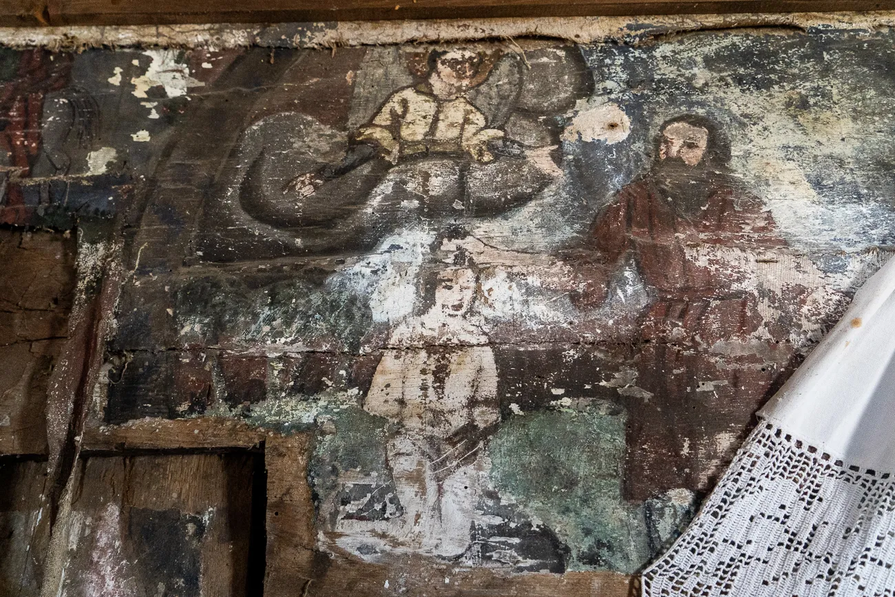 Alter Wandgemälde in einer Holzkirche mit Figuren und abblätternder Farbe